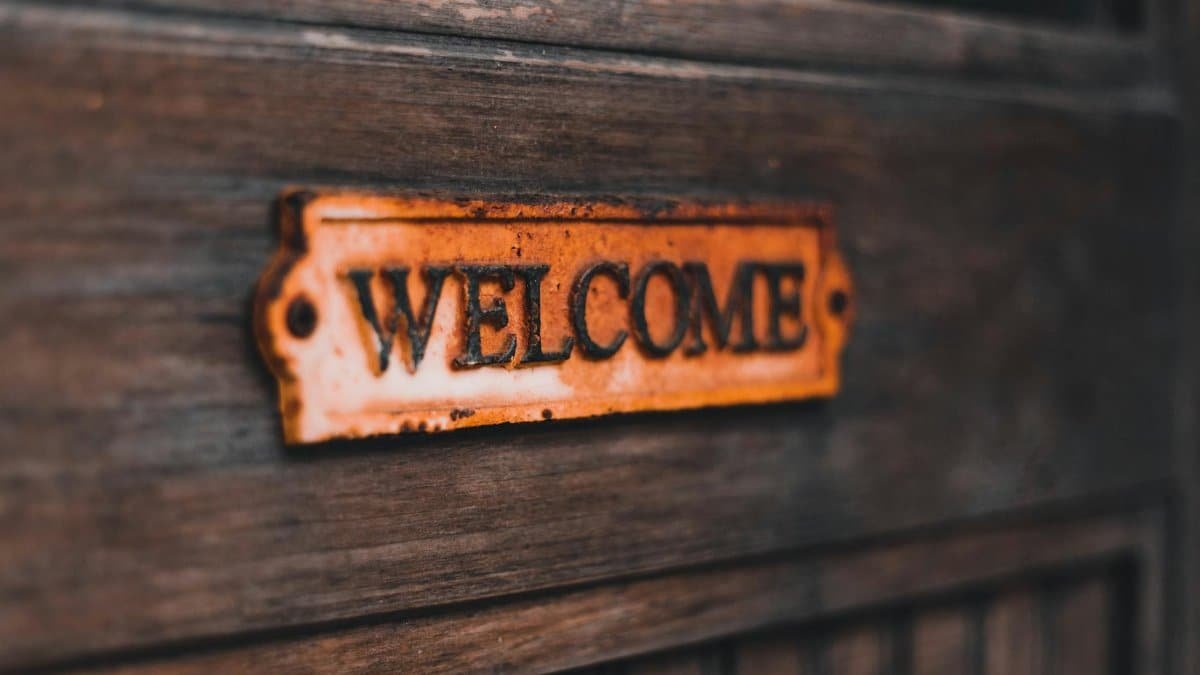 Close-up of a rusty vintage welcome sign on a wooden surface, creating a warm, rustic feel.