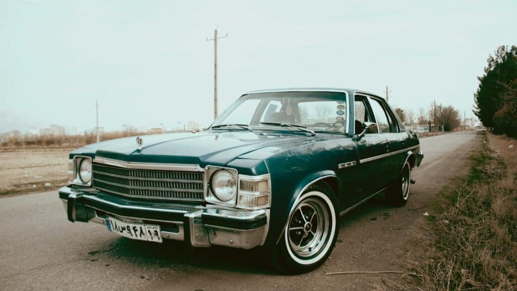 A beautifully restored classic blue vintage car parked on an open countryside road.