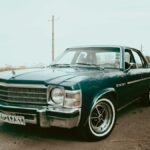 A beautifully restored classic blue vintage car parked on an open countryside road.