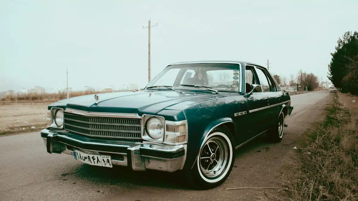 A beautifully restored classic blue vintage car parked on an open countryside road.