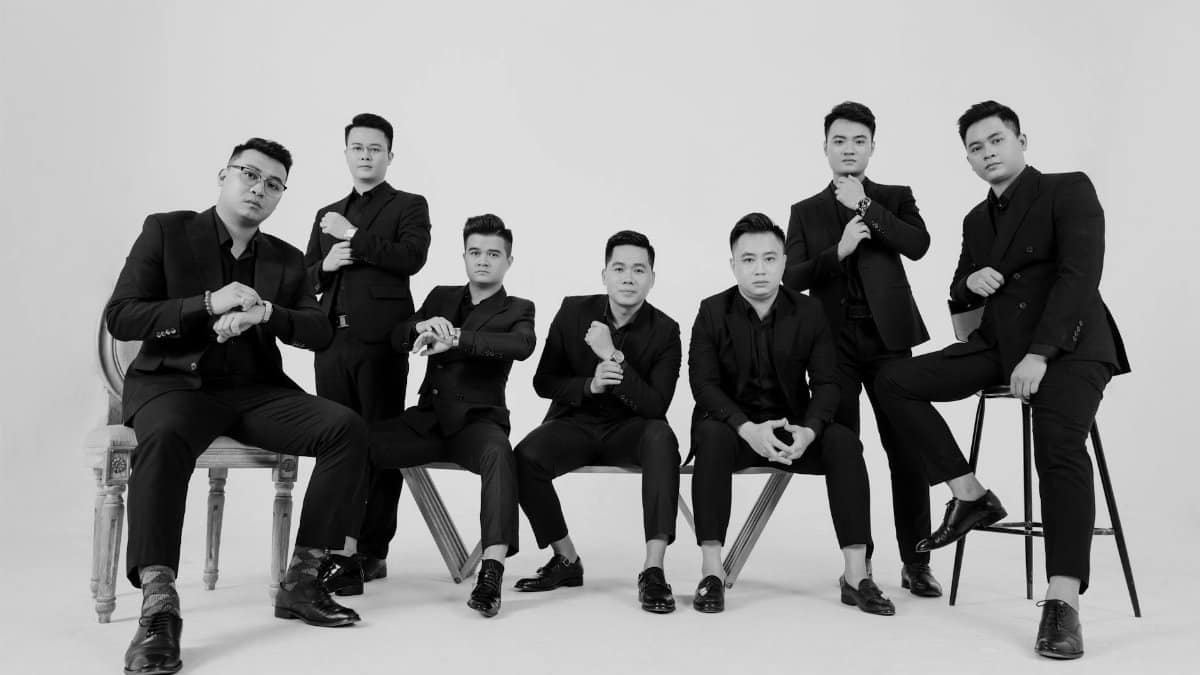 Stylish black and white portrait of seven men posing in suits, demonstrating elegance and fashion.