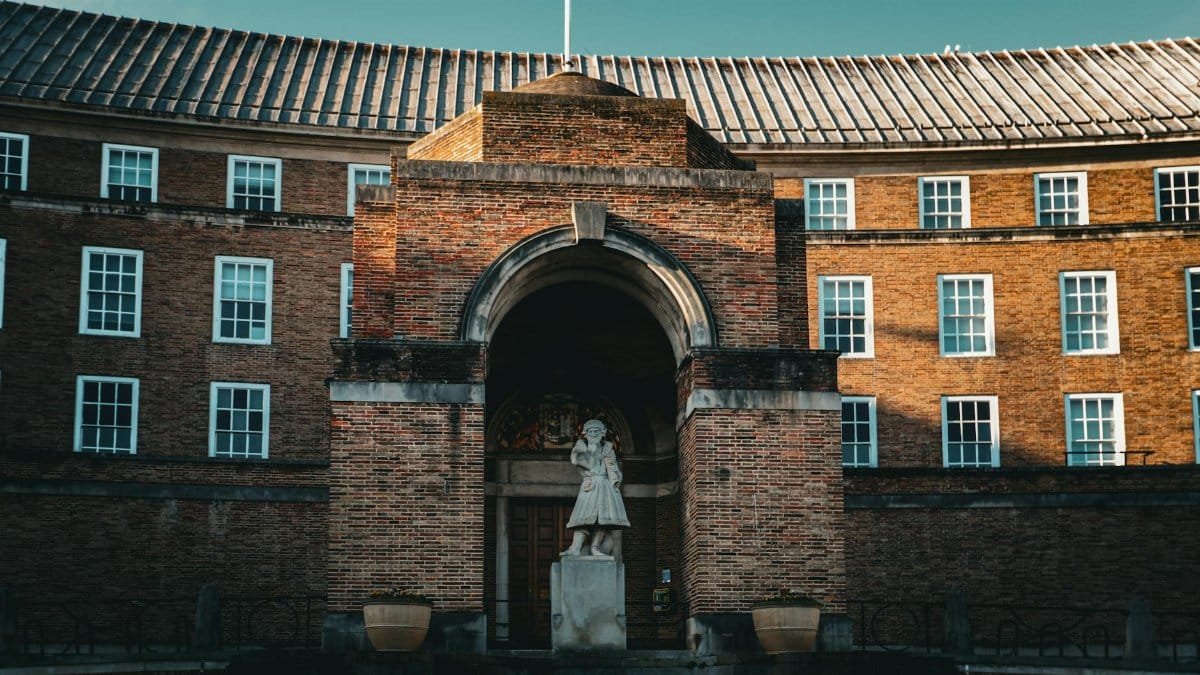 Statue outside a grand brick building under a clear sky.