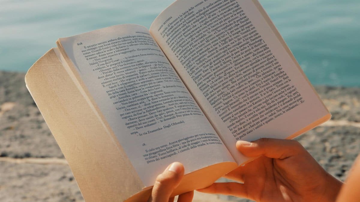 A person enjoys reading a book by the seaside in Syracuse, Sicily.