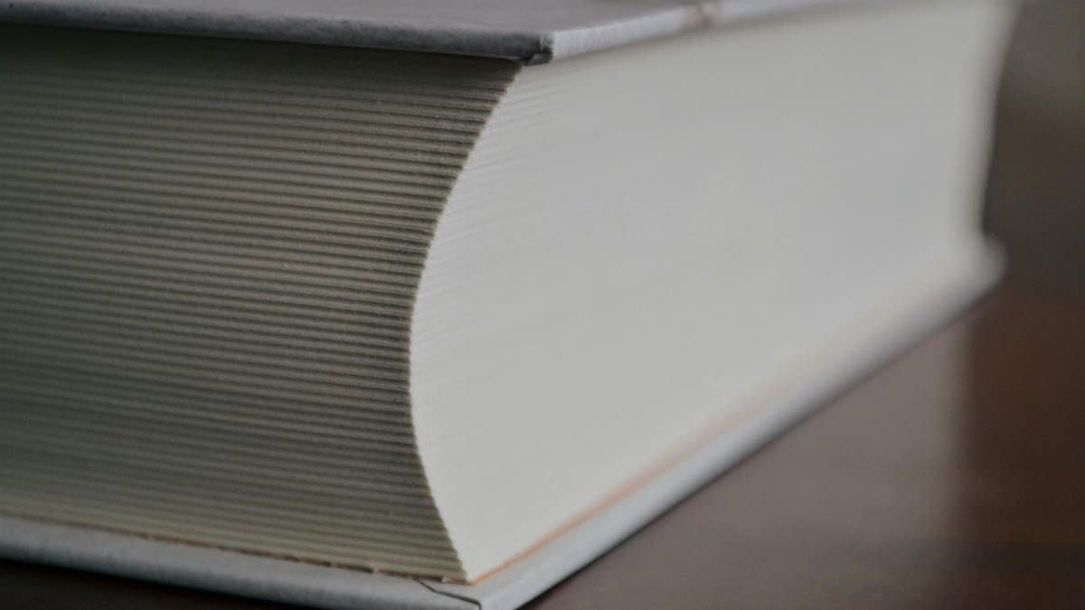 Close-up image of a thick hardcover book on a wooden table.