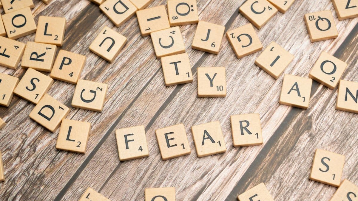 Scrabble tiles on wood surface spelling 'fear', representing emotions like dread and anxiety.