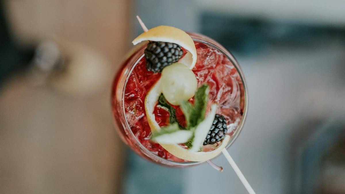 Top view of a vibrant berry cocktail with fruits and ice, garnished elegantly.