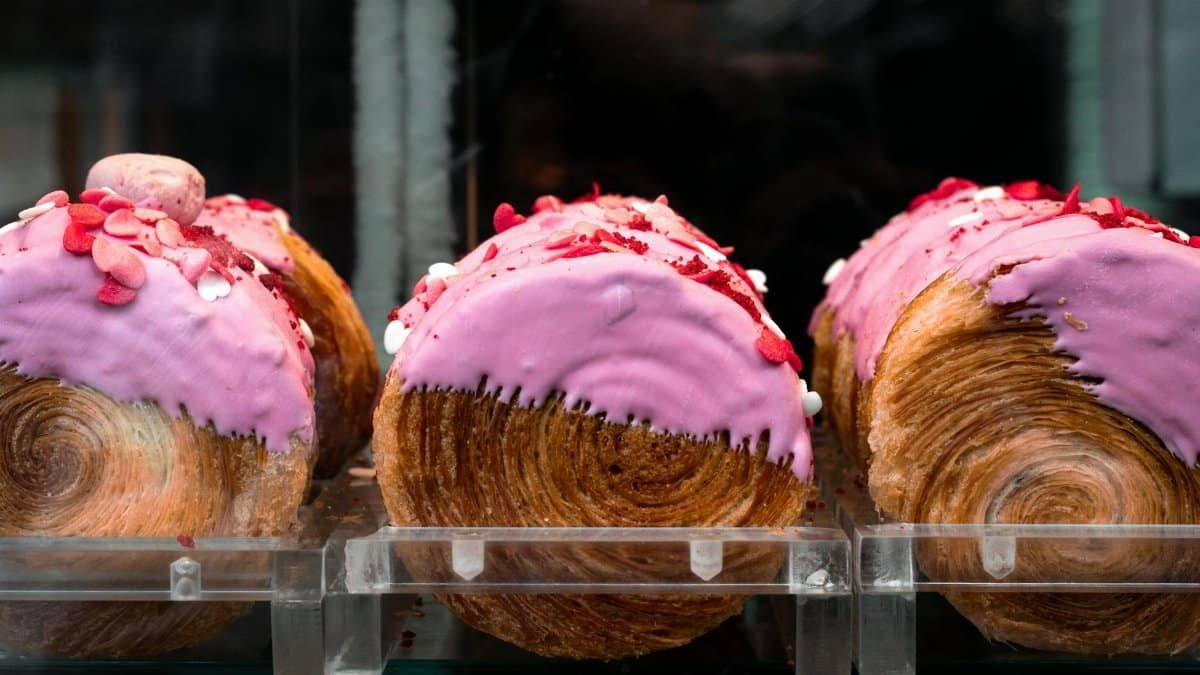 Tempting pink-frosted croissants with heart sprinkles on display in a São Paulo bakery.