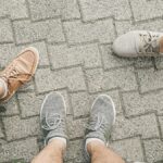 Top view of a group of people standing on paving stones wearing casual sneakers and shoes.