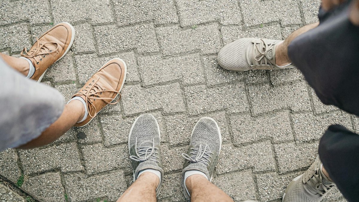 Top view of a group of people standing on paving stones wearing casual sneakers and shoes.