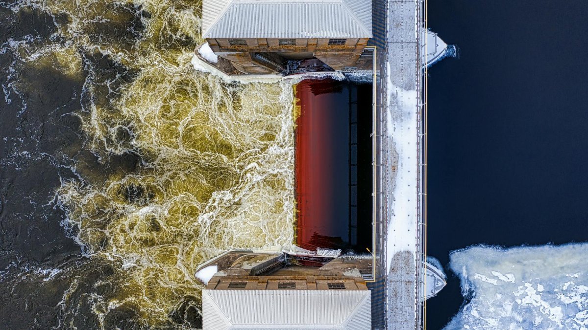Aerial shot of a dam with frozen river and turbulent waters in winter. Captured in Minnesota.