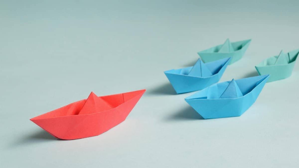 Colorful origami paper boats arranged to depict leadership and teamwork concepts.
