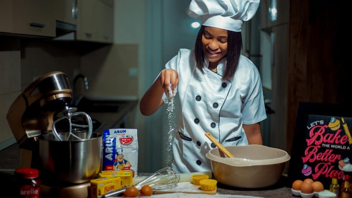 A young chef in a modern kitchen preparing dough with various baking ingredients.