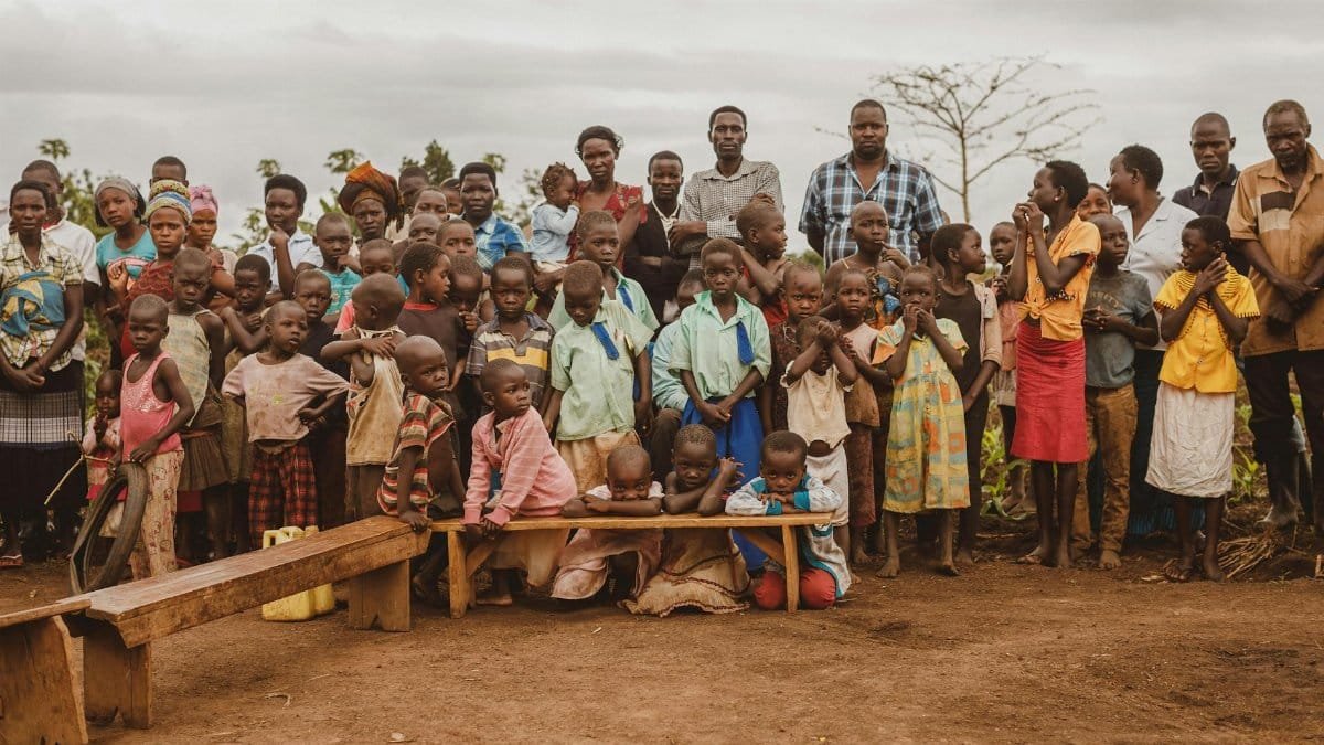 A diverse community gathering in Masindi, Uganda, featuring adults and children together outdoors.