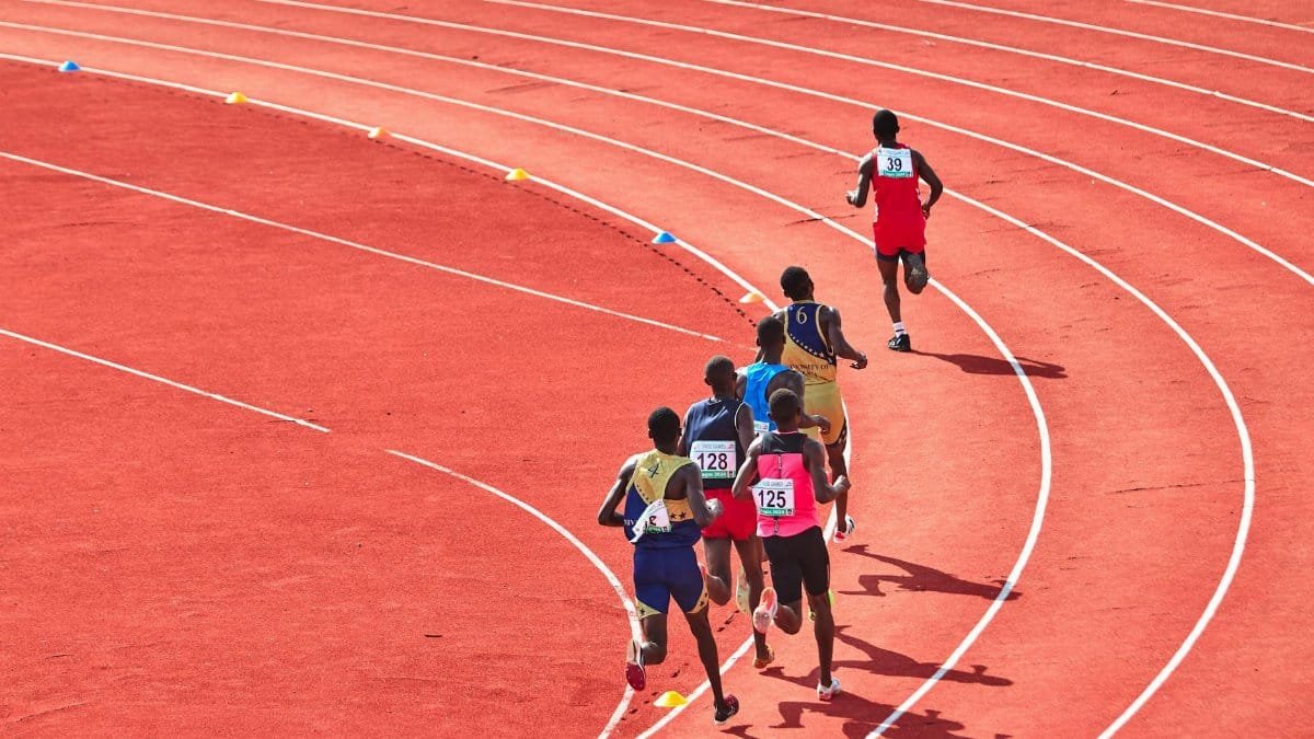 A group of athletes running on a curved outdoor track in a competitive race.