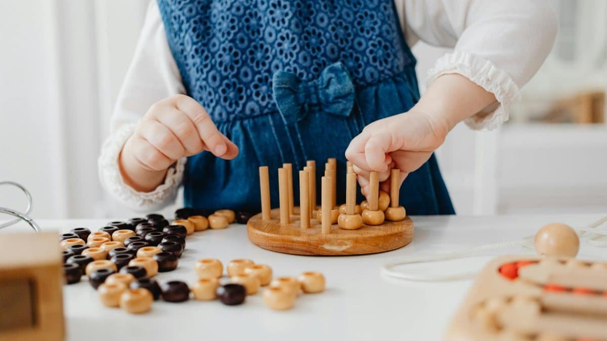 A child interacts with a wooden sorting toy, developing fine motor skills and learning through play.