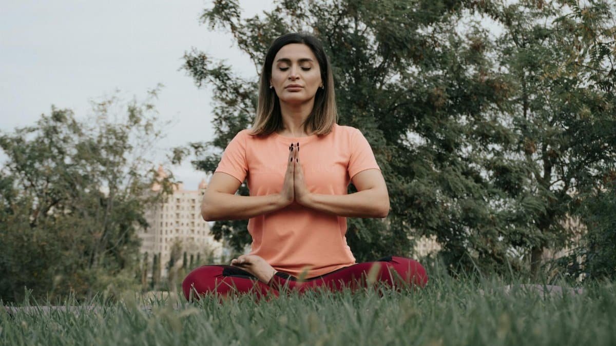 Woman practicing yoga and meditation in park. Enhancing mindfulness and relaxation outdoors.