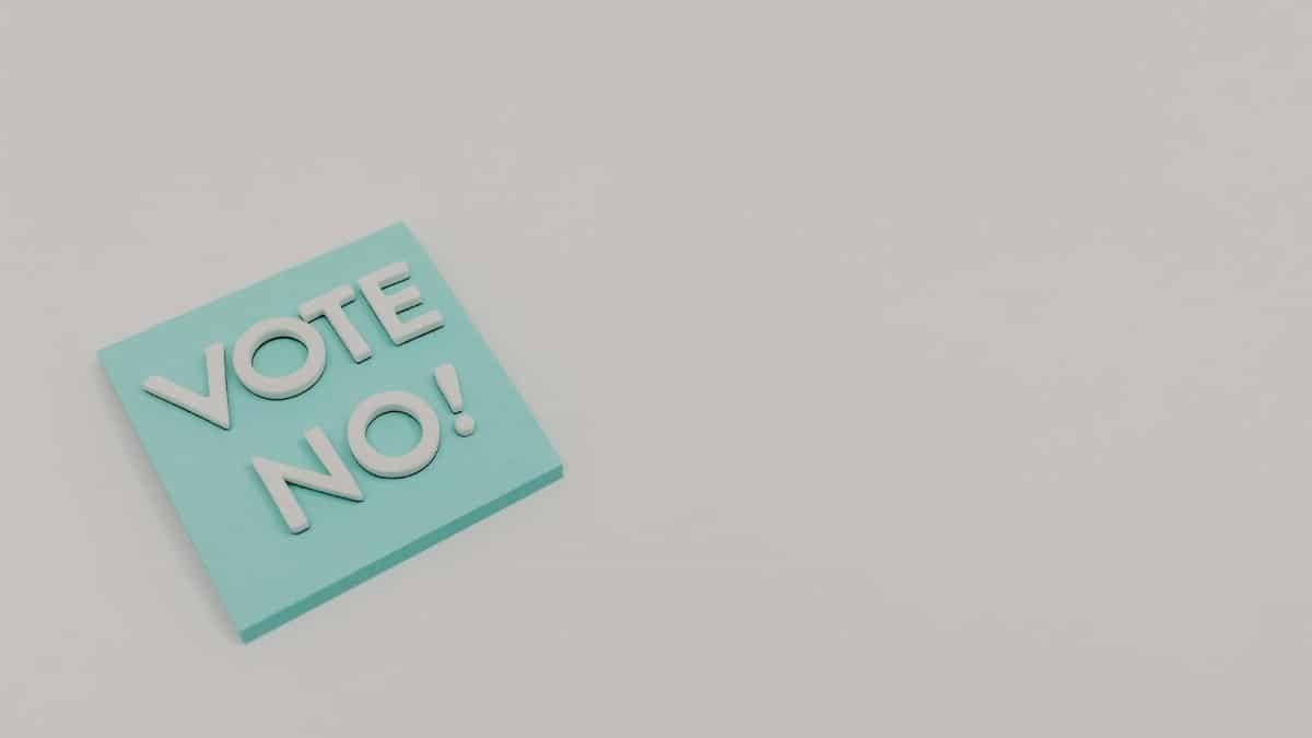 A blue sticky note displaying the message 'Vote No!' on a white surface, minimalistic and impactful.
