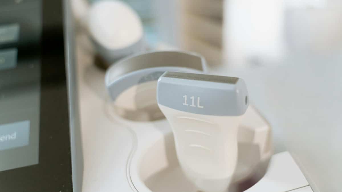 Detail shot of an ultrasound scanner probe in a medical facility setting.
