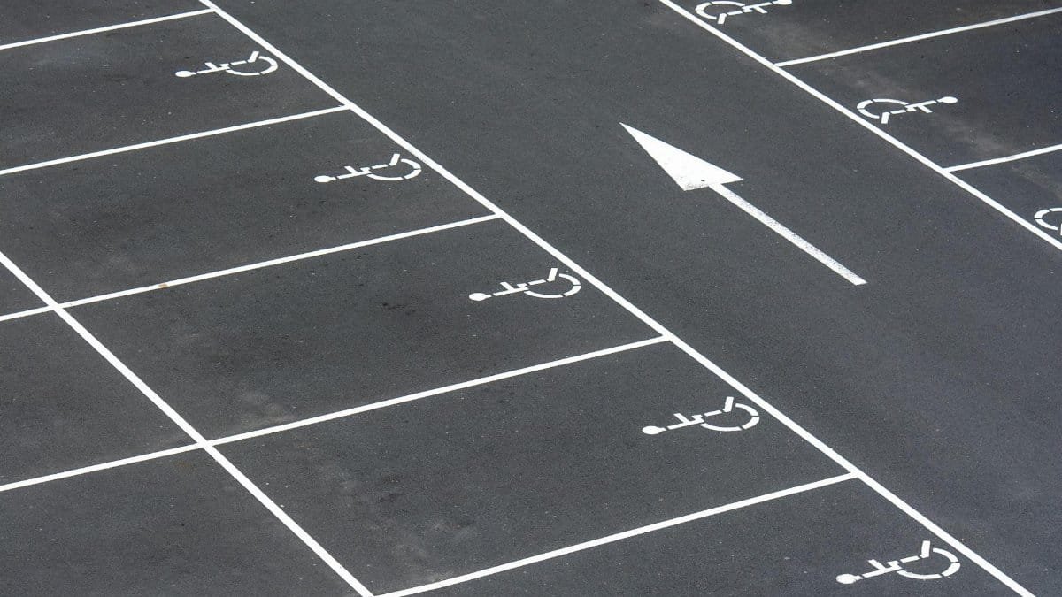 An aerial view of an empty parking lot with handicap spaces and directional arrow.