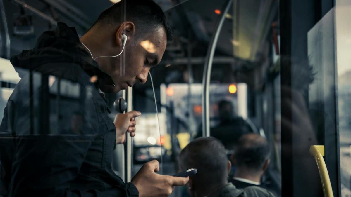 Young man with earphones on bus, engrossed in music during his daily commute.