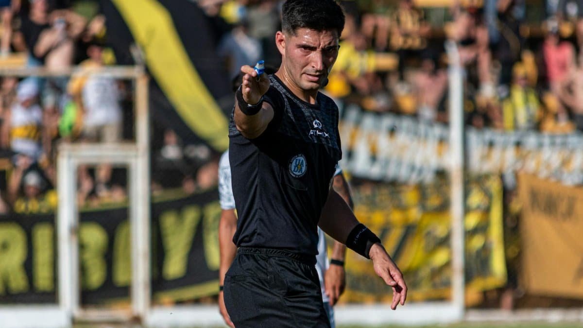 Soccer referee signaling a decision during an intense game outdoors.