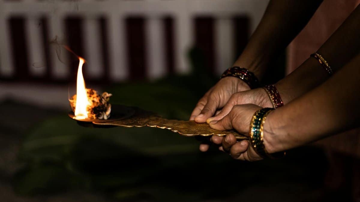 Hands holding a leaf with a burning flame in a traditional cultural ritual.
