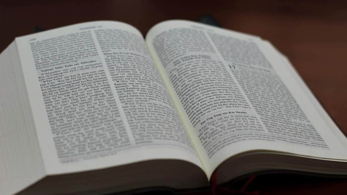 Close-up of an open Bible on a wooden table, showing text and details.