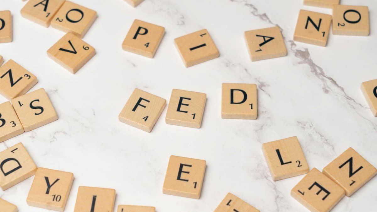 Scrabble tiles arranged to spell 'FED' on a marble surface, symbolizing finance.