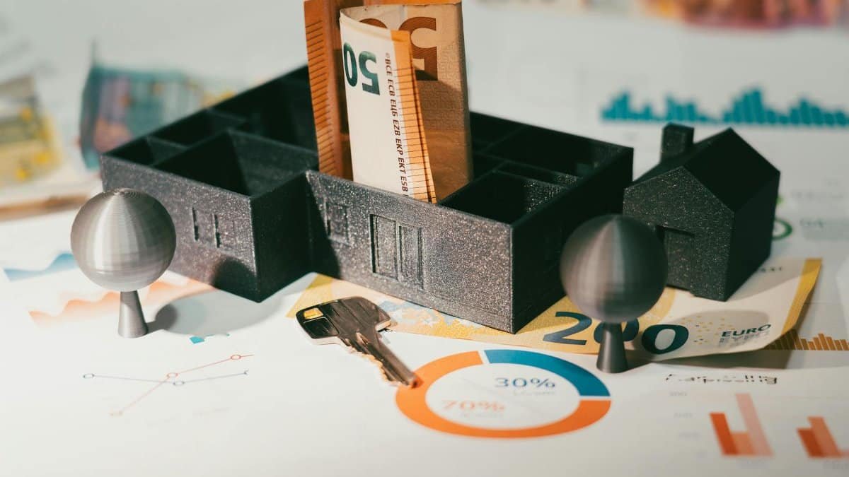 Euro notes with house model and financial charts symbolize real estate investment and economic growth.