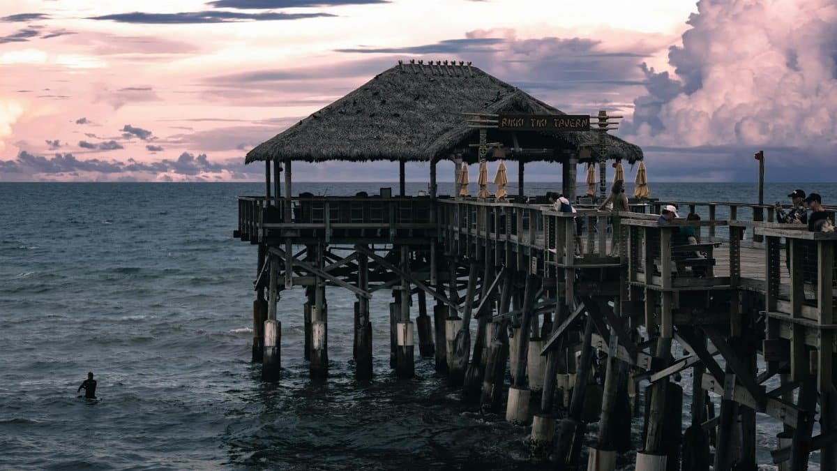 Cocoa Beach pier at sunset with tiki hut and ocean views in Florida, capturing a calm seaside ambiance.