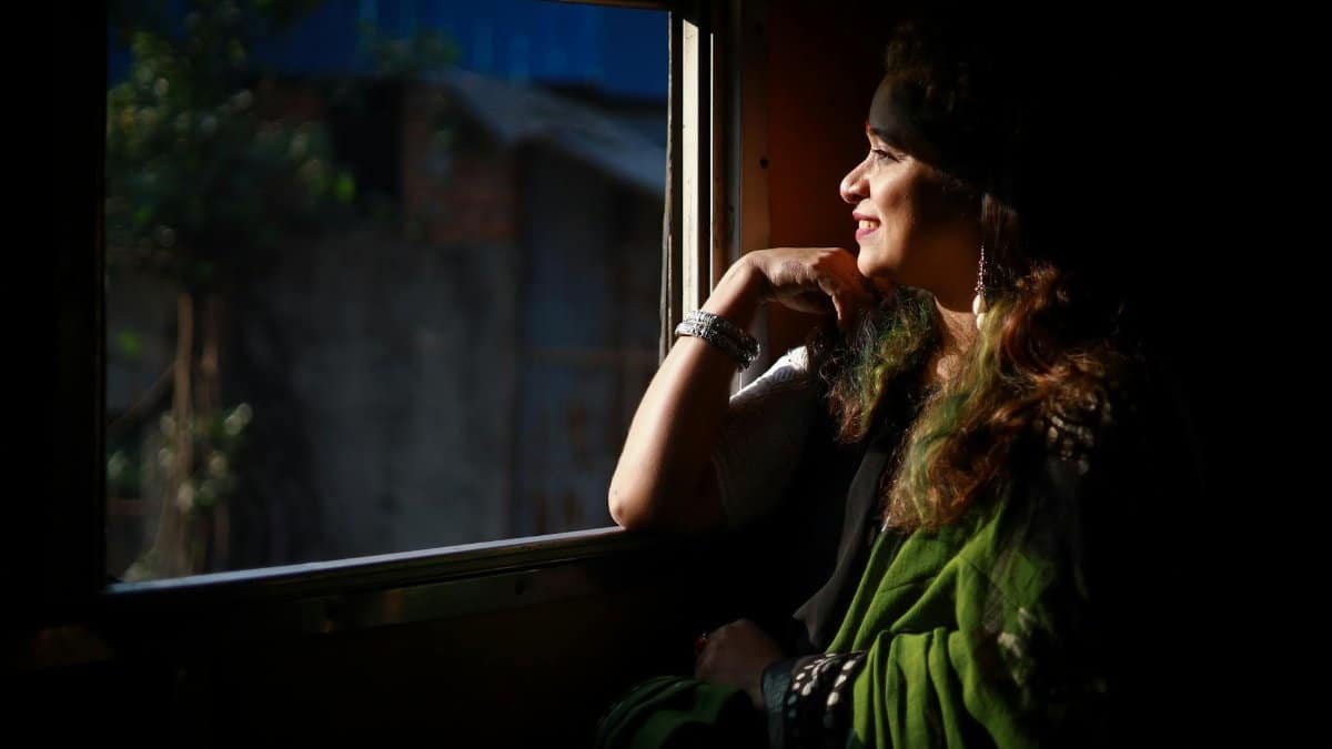 A woman enjoys the sunlight while seated by a train window, embracing serenity.