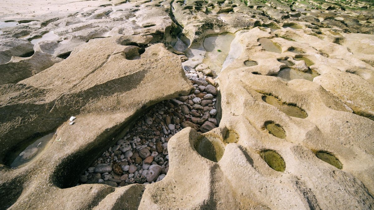 Detailed view of erosion patterns and rock formations on a seaside landscape, revealing natural beauty.