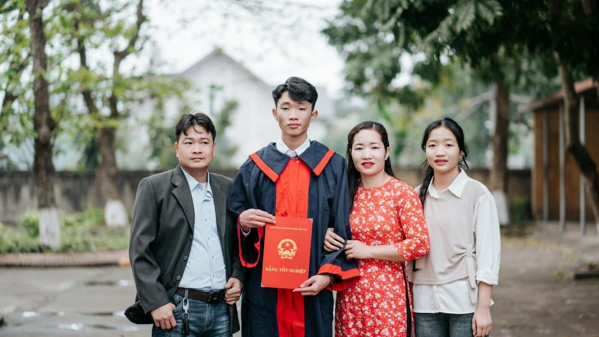 Happy family celebrating graduation outdoors with diploma.