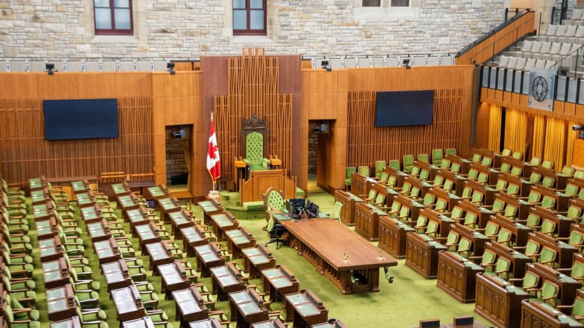 Interior view of the Canadian House of Commons with green seating and wooden decor.