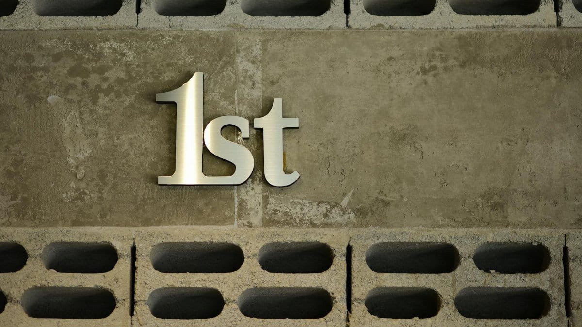 A modern concrete wall featuring the text '1st', symbolizing first place or rank in a bold metallic finish.
