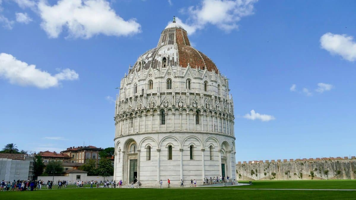 The historic Pisa Baptistery stands majestically against a bright blue sky in Pisa, Italy.