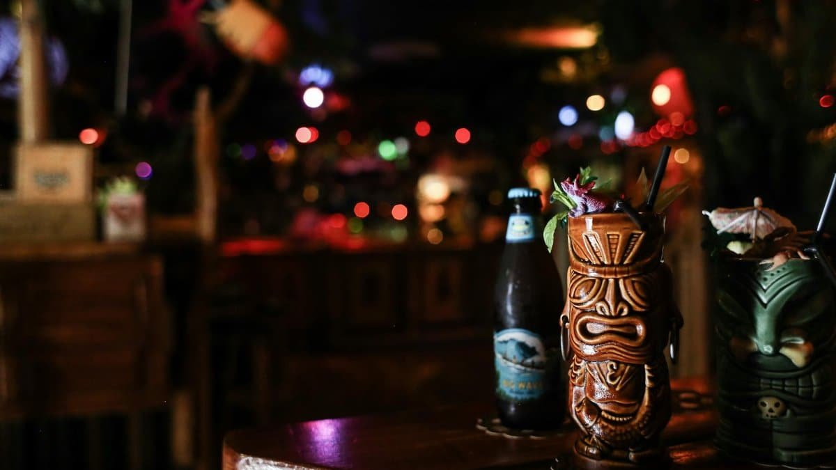 A vibrant tiki bar scene featuring exotic cocktails in tiki mugs with ambient lighting.