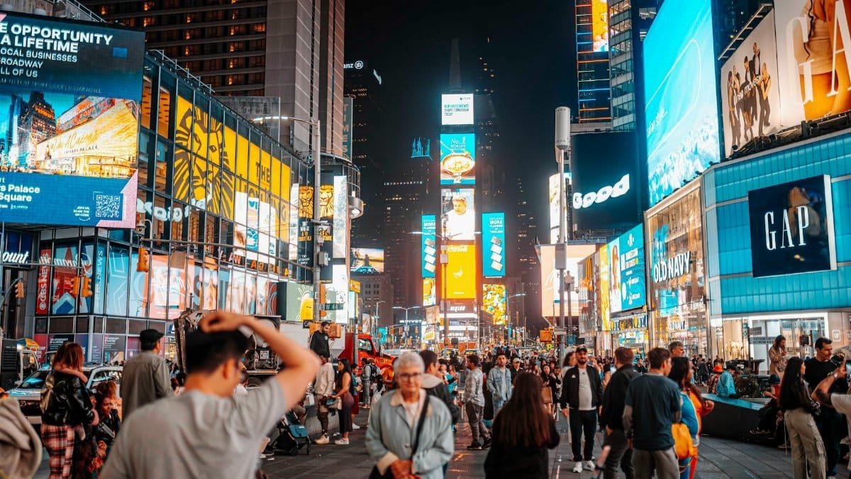 Capture of bustling Times Square at night, showcasing iconic billboards and a lively crowd.