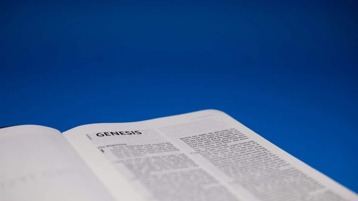 Close-up of an open Bible displaying Genesis against a vivid blue surface.