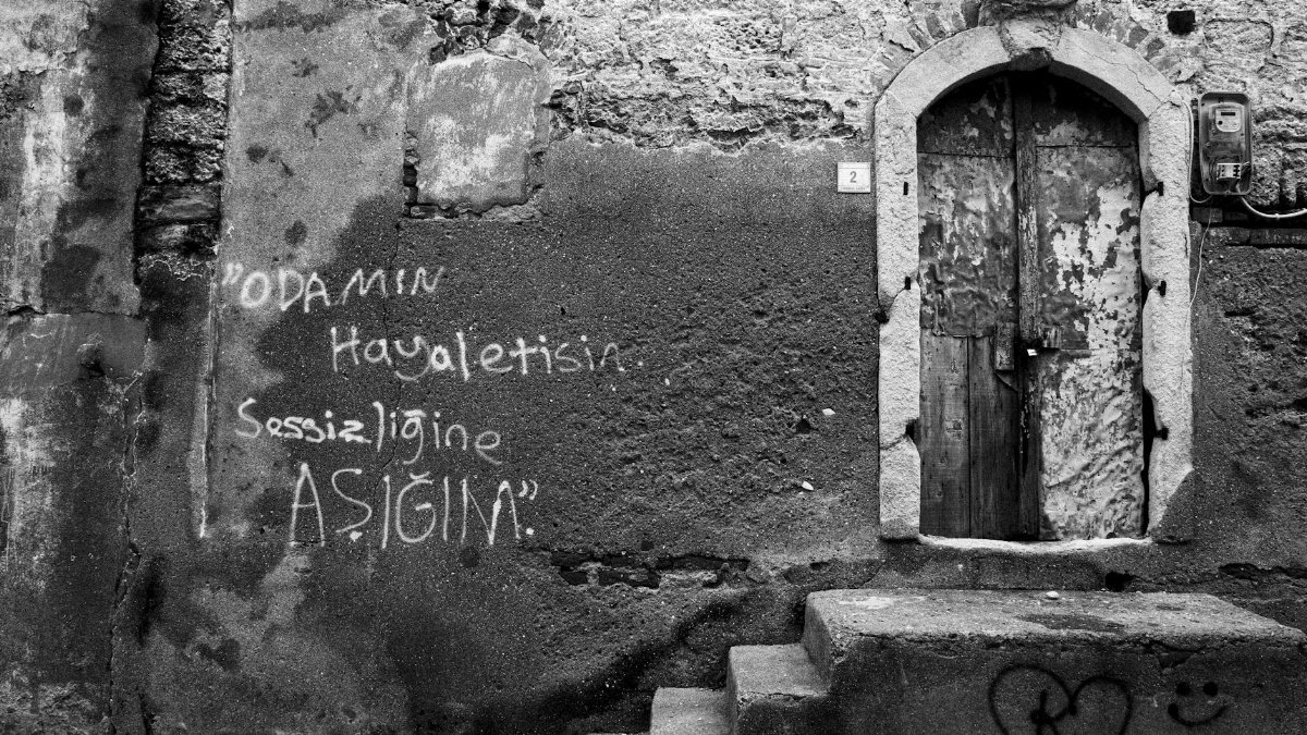 Black and white photo of an old building with graffiti and a weathered door.