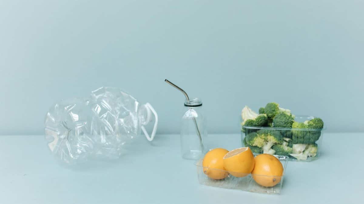 Eco-friendly setup with broccoli, lemons, a metal straw, and reusable containers on a pastel background.