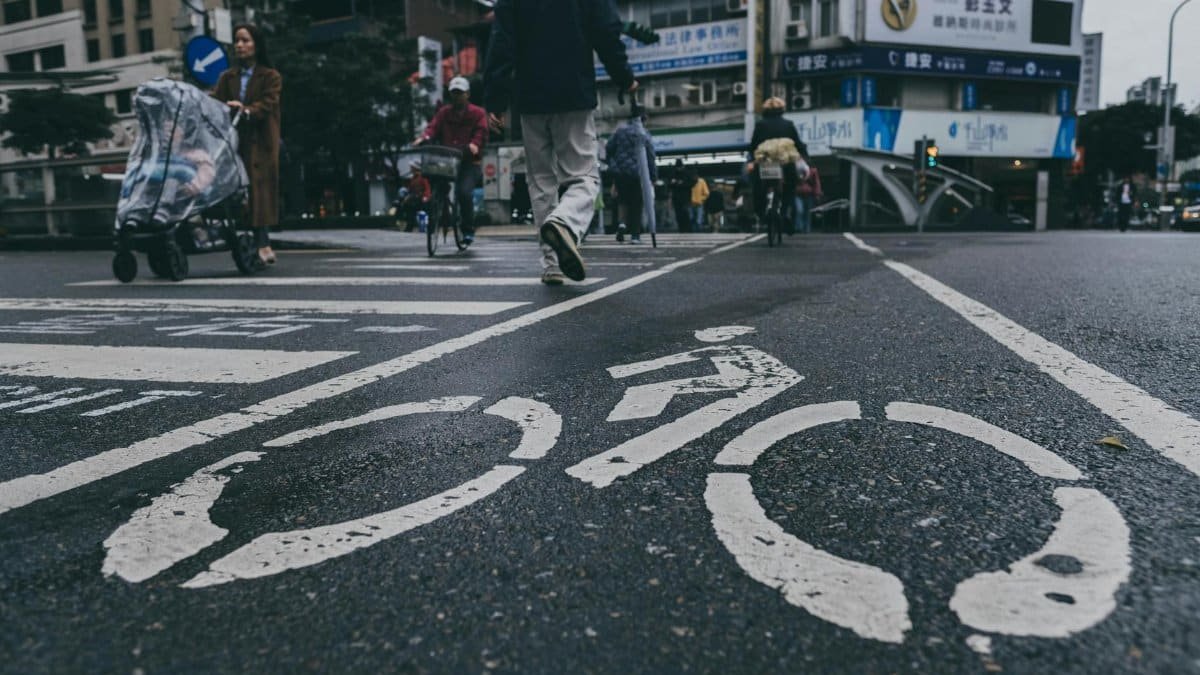 Busy urban street scene in Taiwan with bicycle lane markings and pedestrians crossing.