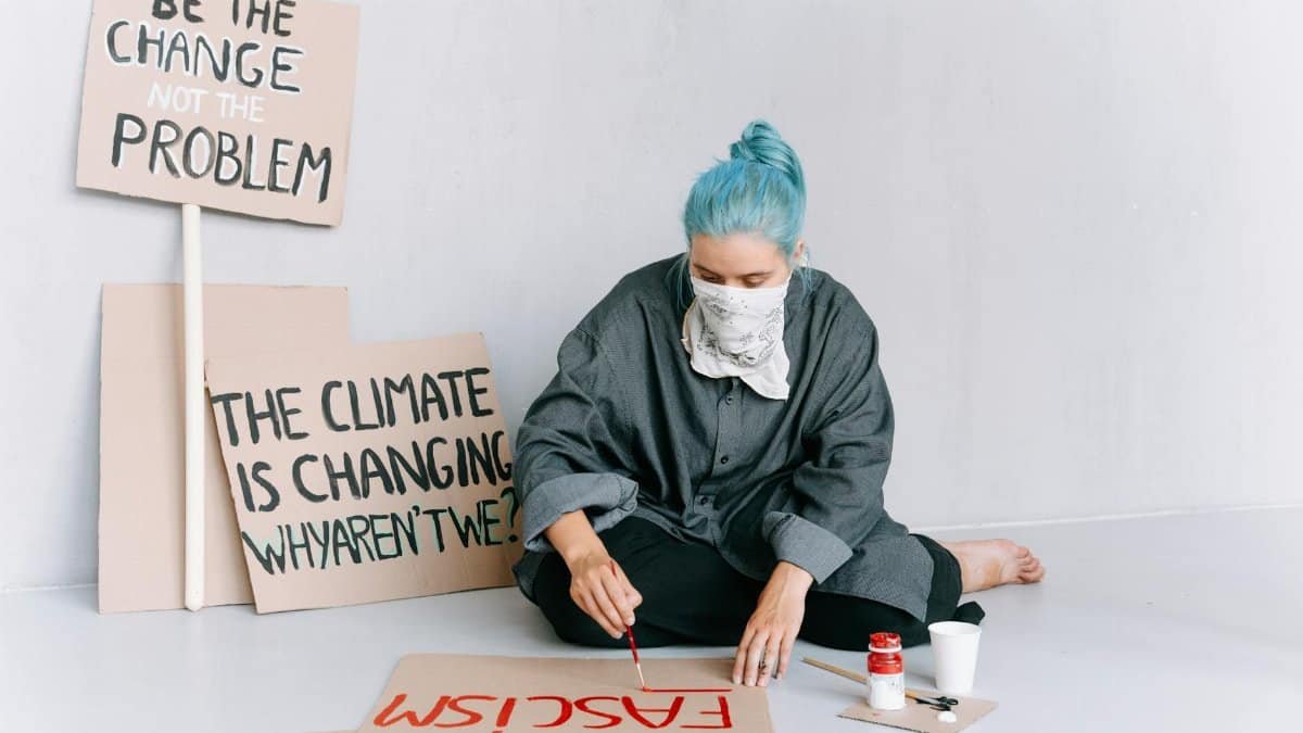 A woman paints protest signs with messages on climate change and social activism.