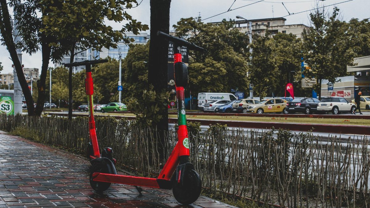A vibrant red electric scooter parked on a wet sidewalk in Bucharest, showcasing urban mobility.