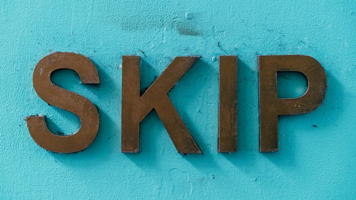 Close-up of brown 'SKIP' letters on a textured turquoise wall for design inspiration.