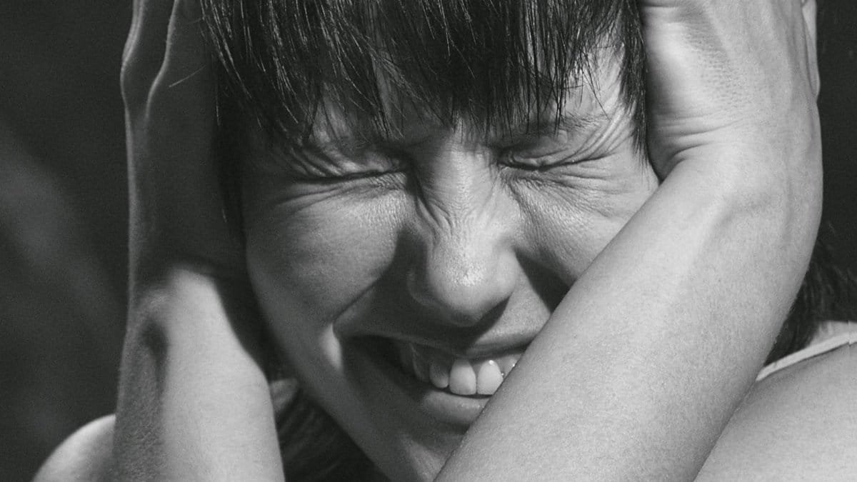 Emotional black and white close-up portrait of a woman expressing pain and frustration.