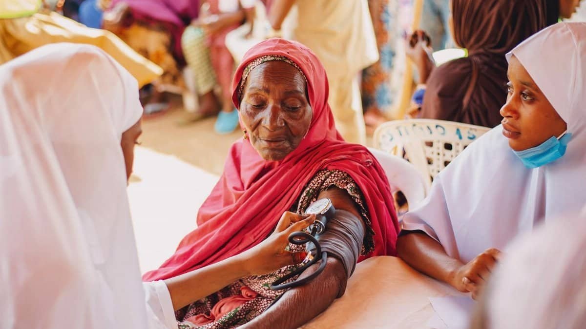 An outdoor health checkup for the elderly in Kaduna, Nigeria, emphasizing community care.