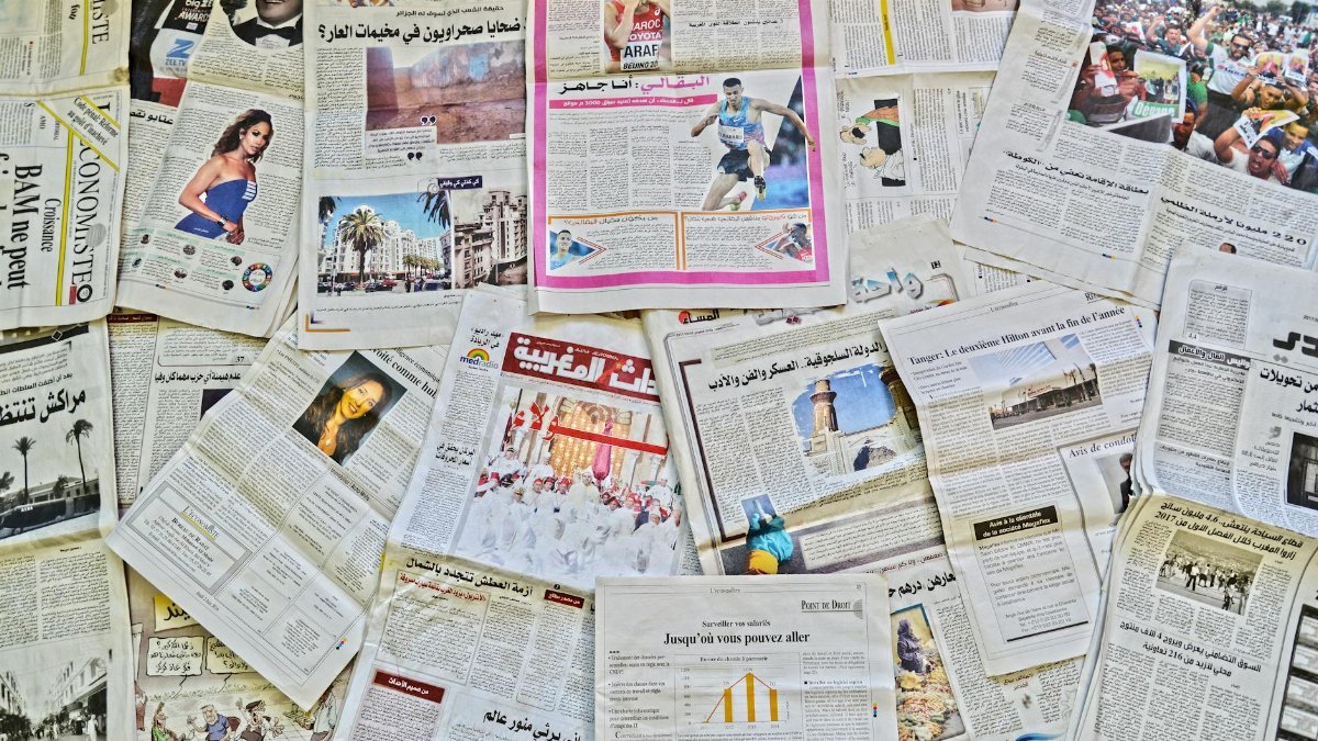 A vibrant array of newspapers laid out in Fès, showcasing diverse stories.
