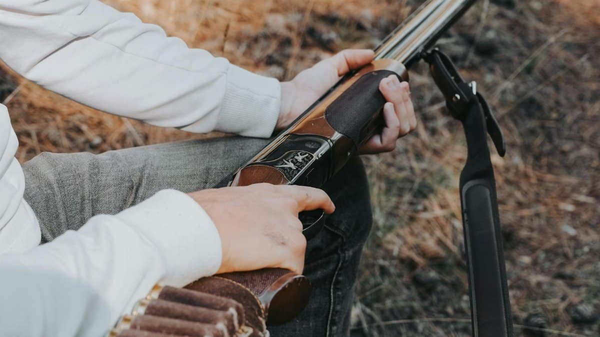 Close-up of a person loading a shotgun outdoors, ready for hunting.