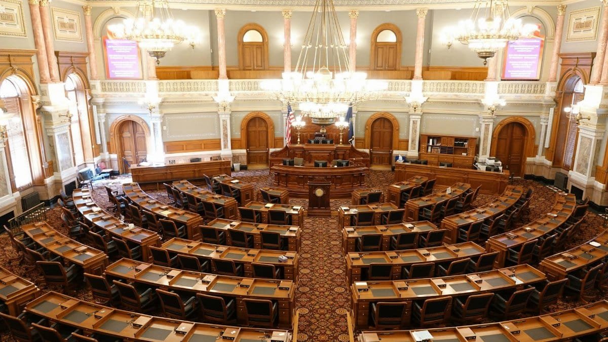 Wide view of an ornate legislative chamber with empty seats and chandeliers.